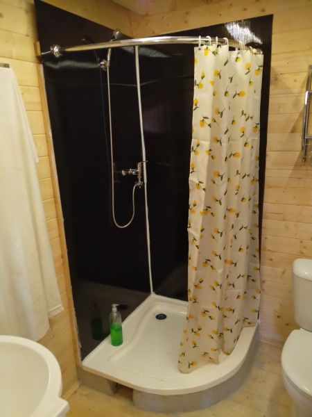 Sprchový kout na chatě s květinovým závěsem a podlahou s dřevěným dekorem.