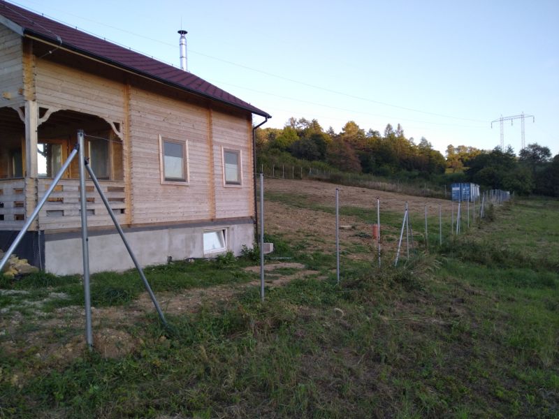 Dřevěná chata v Horní Breznici na okraji lesa s novým oplocením.