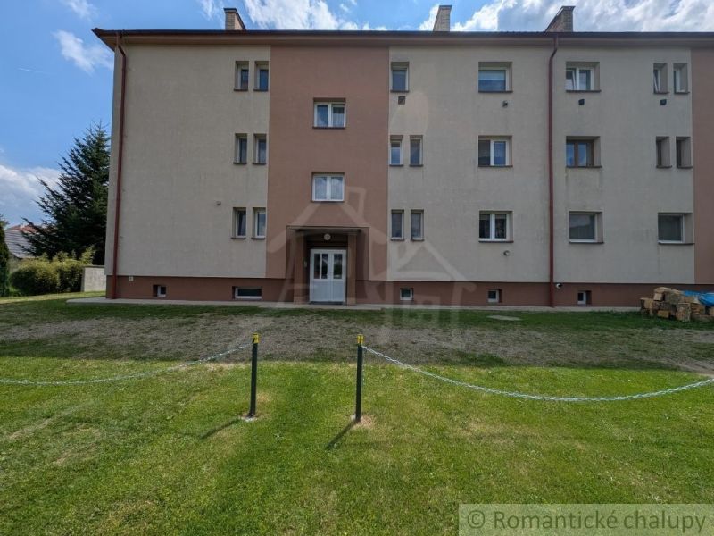 Bytový dům v Medzilaborcích se zeleným dvorem, třípatrový a světlé fasády.