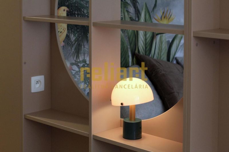 Designová lampa na poličce s tropickou tapetou v 1-pokojovém bytě.