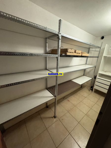 Úložný prostor v rodinném domě s kovovými regály a dlažbou na podlaze.