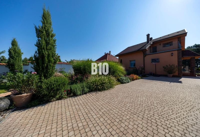 Rodinný dům na Bratislavské ulici v Malinově obklopený udržovanou zahradou a dlažbou.