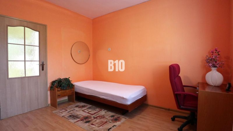 Pokoj v rodinném domě s postelí, psacím stolem a podlahou s dřevěným dekorem.