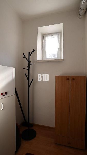 Malá místnost v rodinném domě s věšákem a skříní, podlaha s dřevěným dekorem.