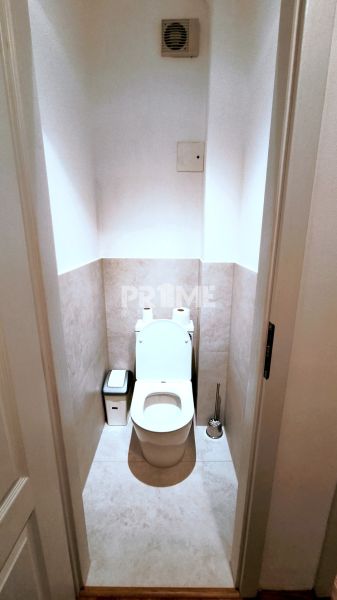 Toaleta v 2-pokojovém bytě s béžovým obkladem a ventilátorem.