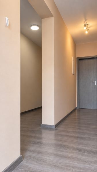 Chodba v rodinném domě s podlahou s dřevěným dekorem a neutrálními stěnami.