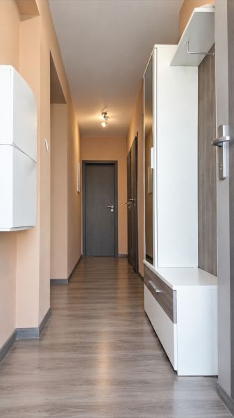 Chodba v rodinném domě s podlahou s dřevěným dekorem a světlými stěnami.