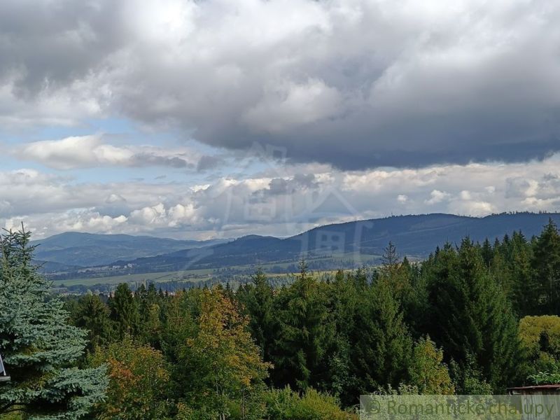 Výhled z chaty v Staškově na kopcovitou krajinu pod zamračenou oblohou.