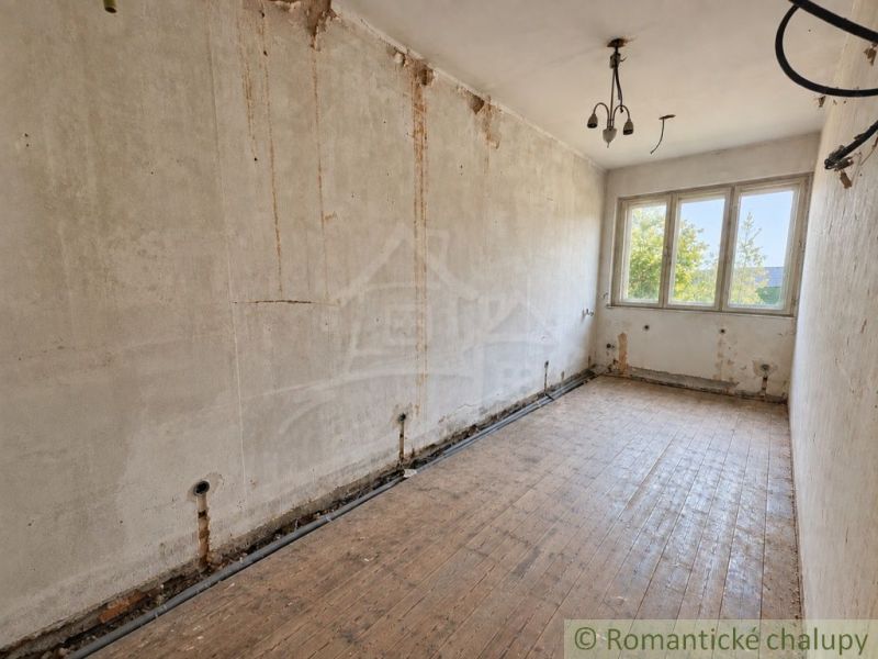Místnost s nedokončenými stěnami a podlahou s dřevěným dekorem v rodinném domě.
