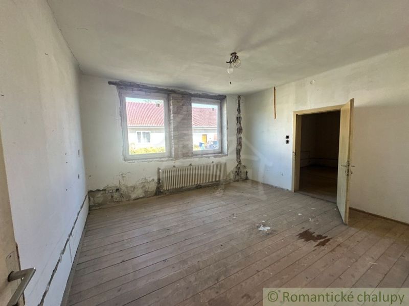 Pokoj v rodinném domě s podlahou s dřevěným dekorem potřebuje rekonstrukci.