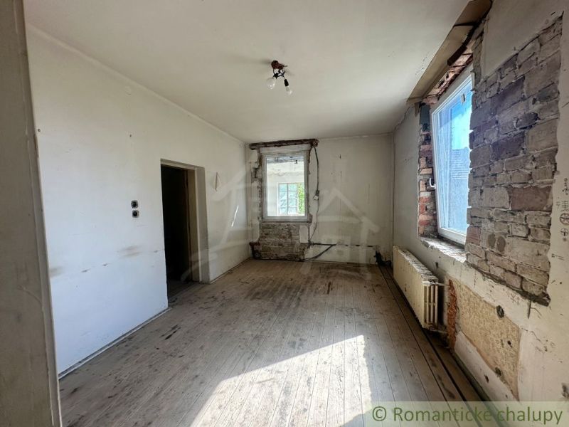 Ošuntělá místnost s podlahou s dřevěným dekorem čekající na renovaci v rodinném domě.