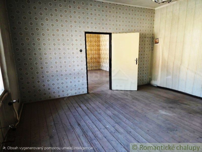 Místnost s tapetami a podlahou s dřevěným dekorem, v pozadí další pokoj.