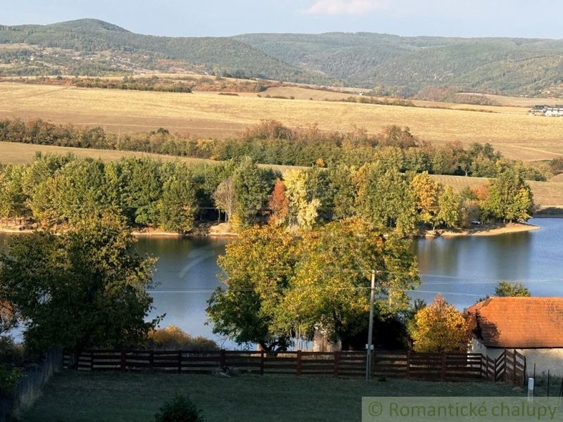 Jezero obklopené podzimními stromy a kopci v zahradách v Krupině.