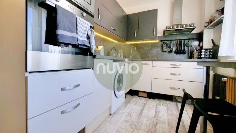 Kuchyně s bílými a šedými skříňkami v 2-pokojovém bytě, podlaha s dřevěným dekorem.